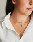 A single dark pearl pendant flanked by gold-filled beads and hung from a fine gold-filled chain. Worn by a model along with assorted other necklaces.
