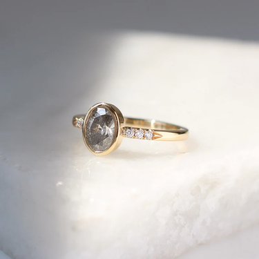 14k Yellow Gold Ring with diamond studs moving towards a 1.07ct Oval Bezel Salt and Pepper Diamond