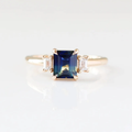 14k Yellow Gold ring with a 1.37ct Trilogy Emerald Cut Blue Sapphire, and 
2 0.19ct straight baguette cut natural white sapphires