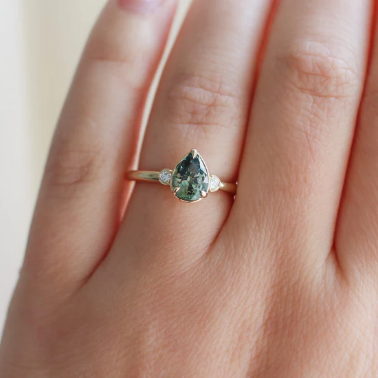 14k Yellow gold ring, Featuring a 1.40ct pear cut natural green sapphire, with
0.06ct round brilliant cut natural Canadian diamonds, GH/VS2 | on model