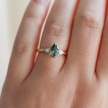 14k Yellow gold ring, Featuring a 1.40ct pear cut natural green sapphire, with
0.06ct round brilliant cut natural Canadian diamonds, GH/VS2 | on model