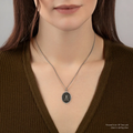 A Sterling Silver Pyrrha talisman With a Talisman depicting a tall mountain with a sun rising over it, including the text "Amor fati" written beneath it | on model