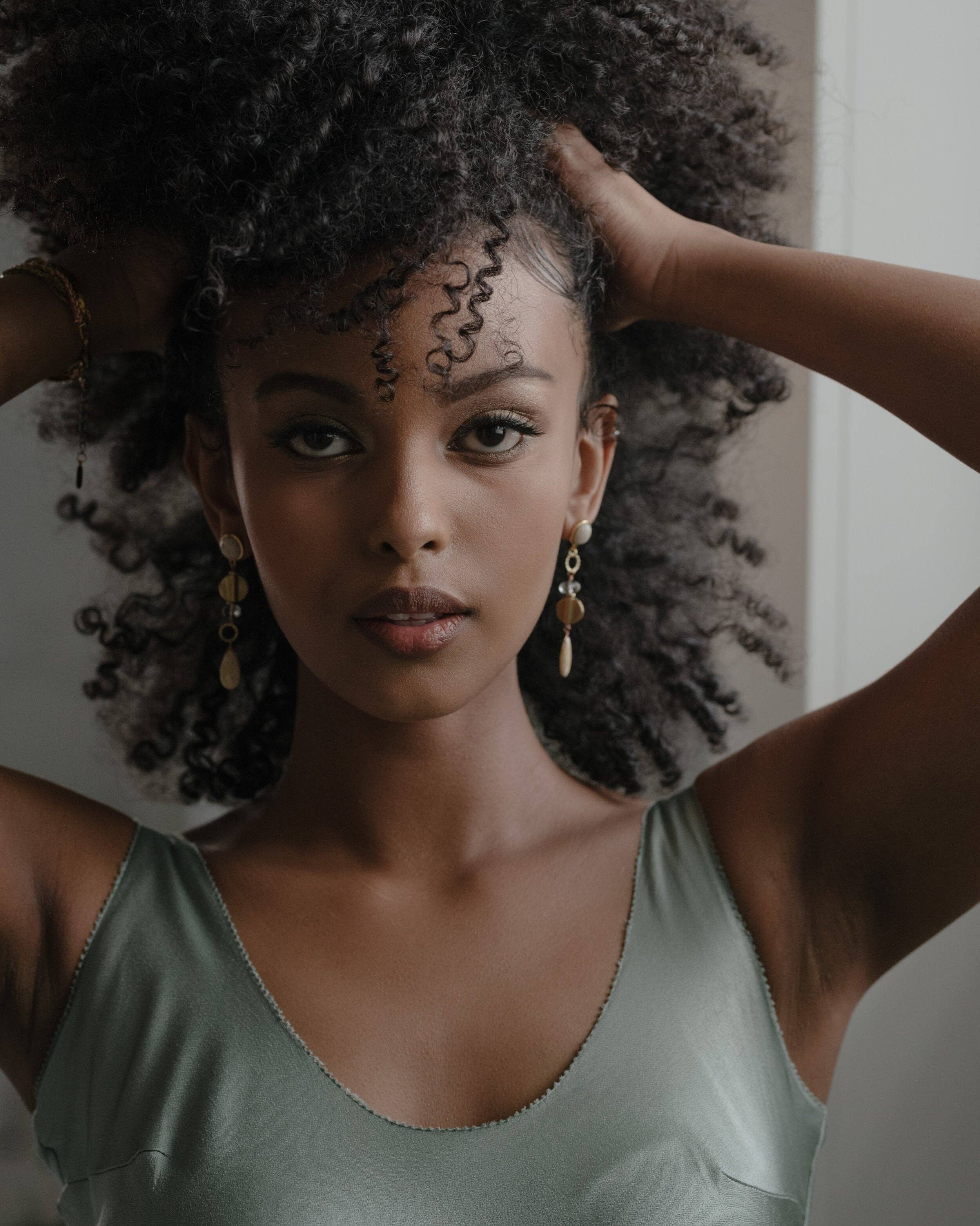 Augustea Earrings, with a hand cut coral Jade for the bottom teardrop and the top round stud, set in 14K gold-plated brass with Vermeil earring posts. Accented with fair-trade recycled brass, including a Peach Moonstone | on model