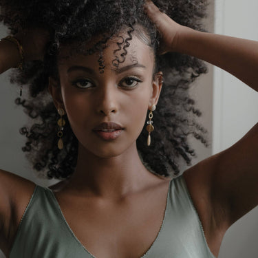 Augustea Earrings, with a hand cut coral Jade for the bottom teardrop and the top round stud, set in 14K gold-plated brass with Vermeil earring posts. Accented with fair-trade recycled brass, including a Peach Moonstone | on model