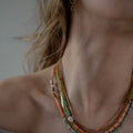 Belinay Necklace featuring a combination of shiva shell, dyed coral, hand-cut gemstones, and brass accents. With multiple strands and a variety of colours including Hessonite, Peridot, Yellow Jade, Turquoise, Dyed Coral, and Shiva Shell. | on model