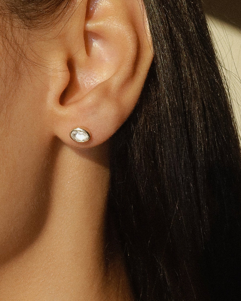 14k Yellow gold Plated sterling silver bezel studs, in an oval shape with a white topaz gemstone | on model