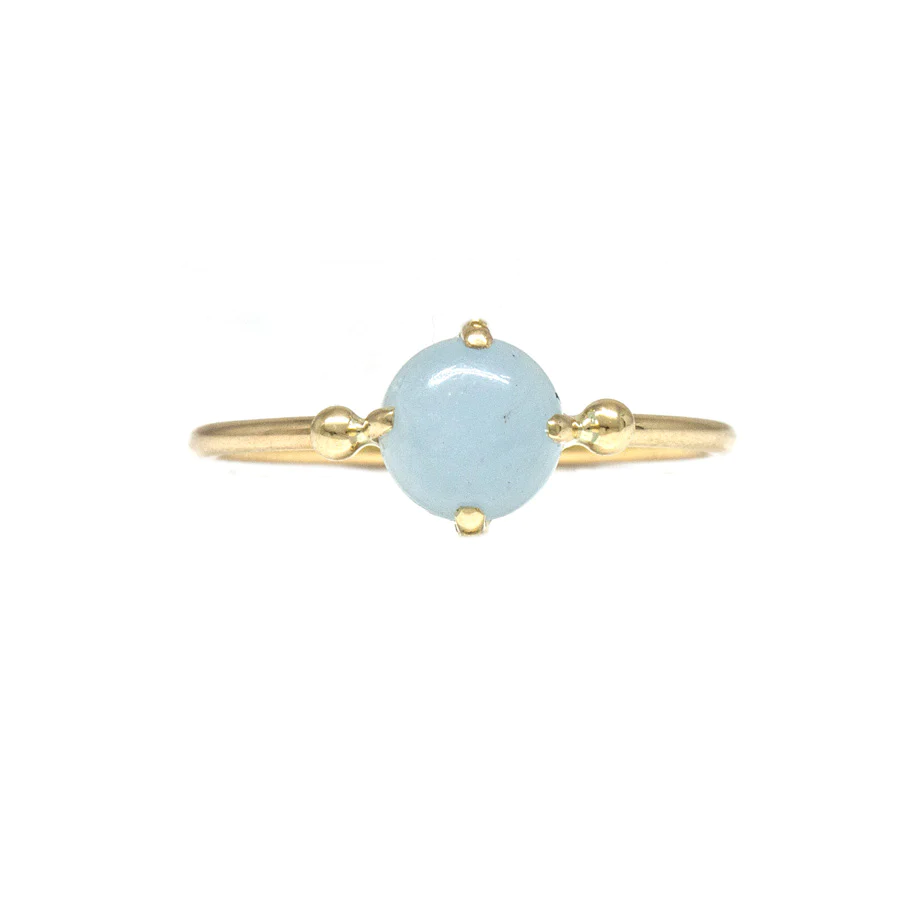 A round slim gold band features a smooth cabochon cut Aquamarine stone resembling a water droplet