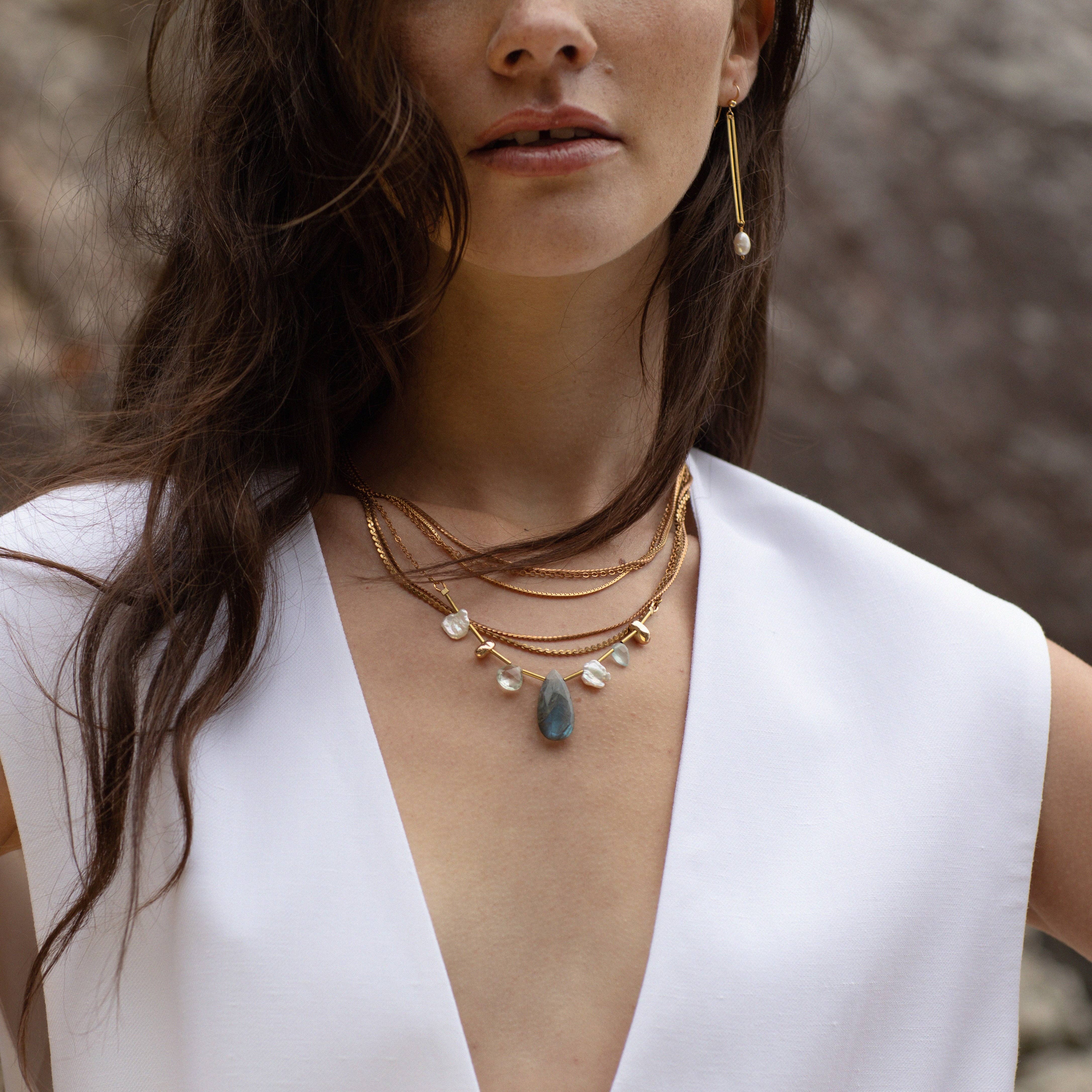 Seda Necklace featuring an asymmetrical assortment of gemstones and Freshwater Pearls in unique colours and textures combined with layers of reclaimed brass chains and gold-plated brass details.  | on model