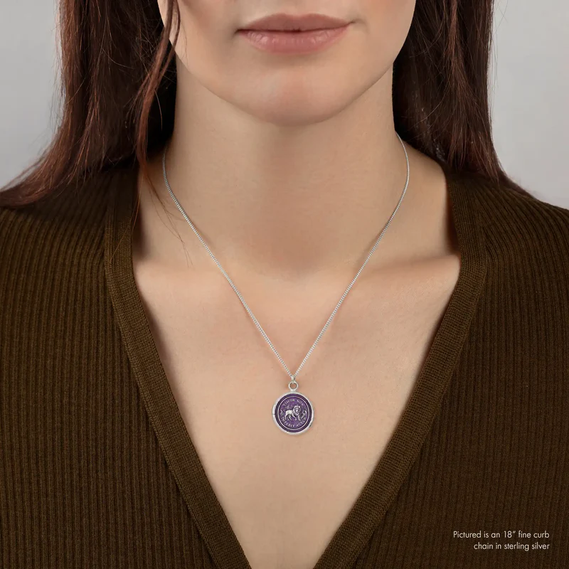 A Talisman necklace withe a violet colored background depicting a Lion standing with flames surrounding him, with the text "imor Non Impedit Actum", on the top and bottom of the talisman. | on model