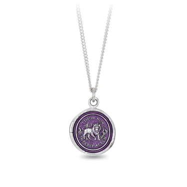 A Talisman necklace withe a violet colored background depicting a Lion standing with flames surrounding him, with the text "imor Non Impedit Actum", on the top and bottom of the talisman.