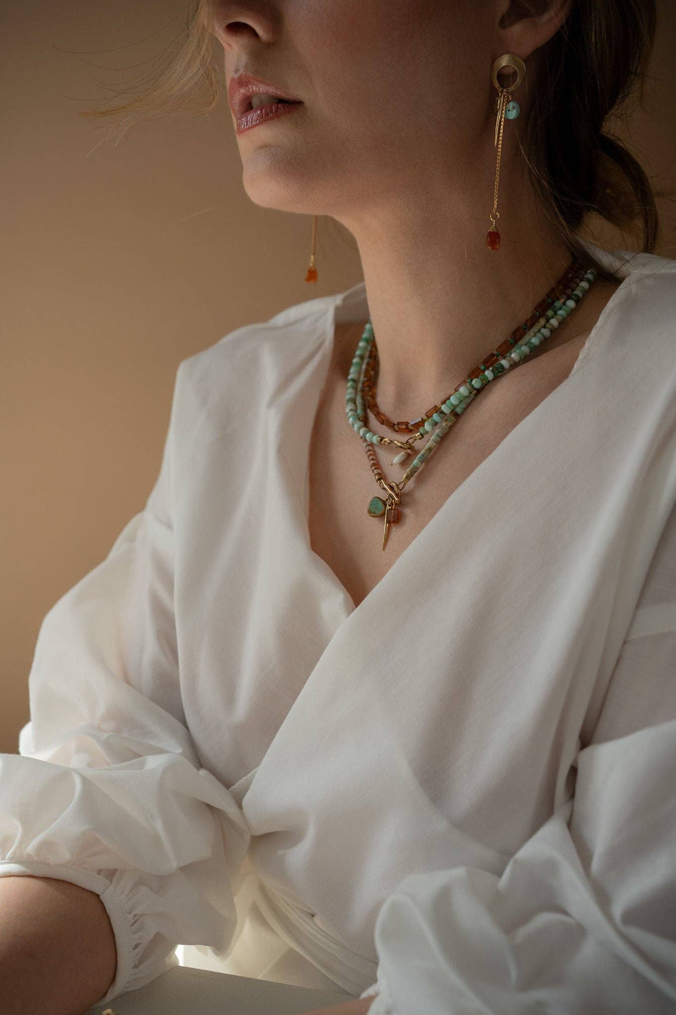 necklace featuring a striking combination of brass-edged Turquoise, Hessonite, and Moonstone beads, with a brass toggle clasp and a 14K gold-plated brass spike charm. | on model