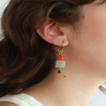 Short Two Toned earrings adorned with colorful Orange and Green geometric pieces | on model