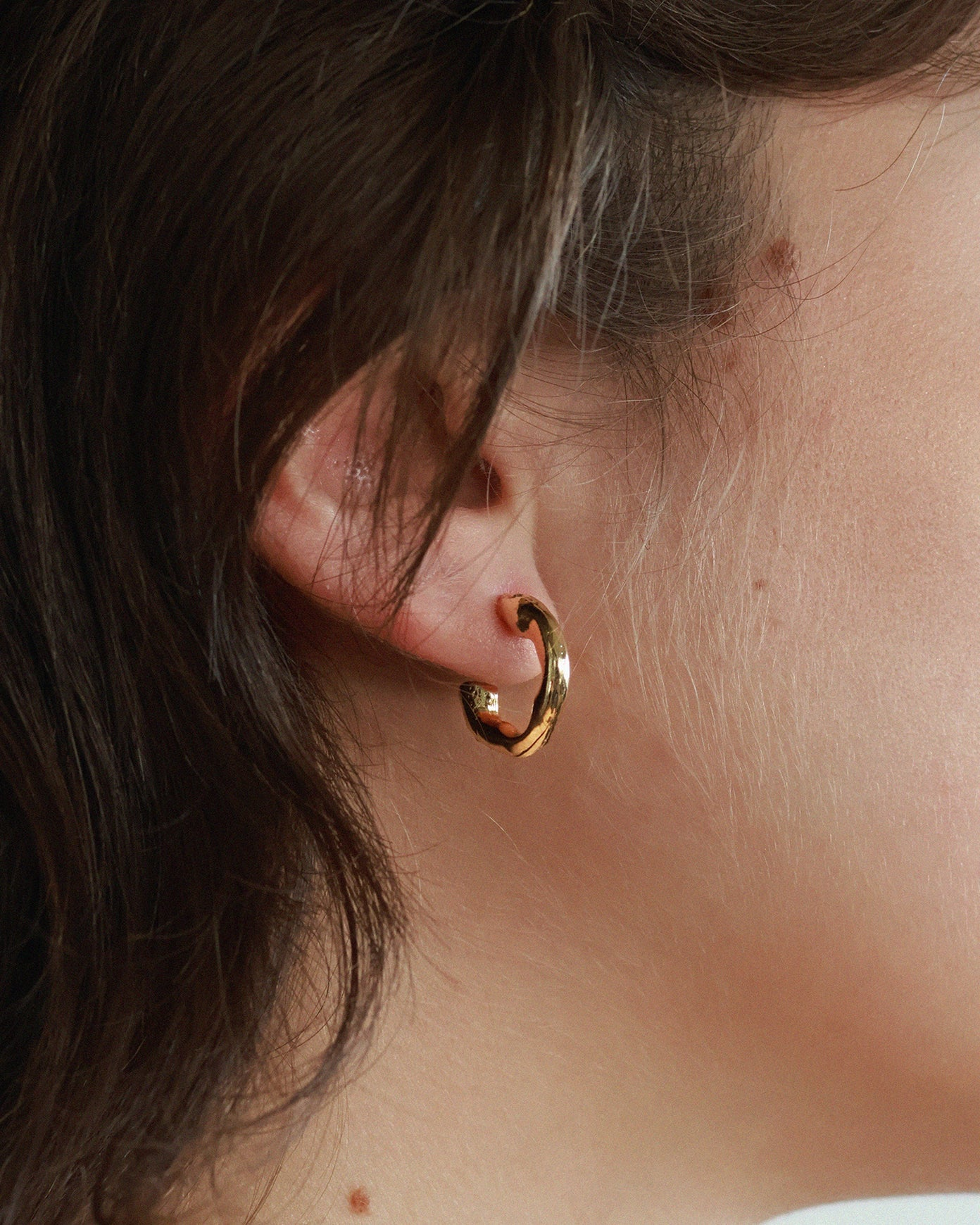 Organic-shaped matt gold hoop earrings | on model