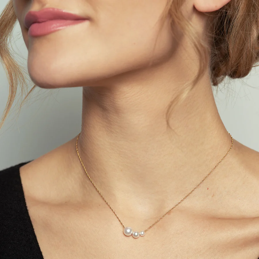 Handcrafted from 14k-karat gold, this delicate necklace is anchored with three luminous pearls in gradual sizes | on model