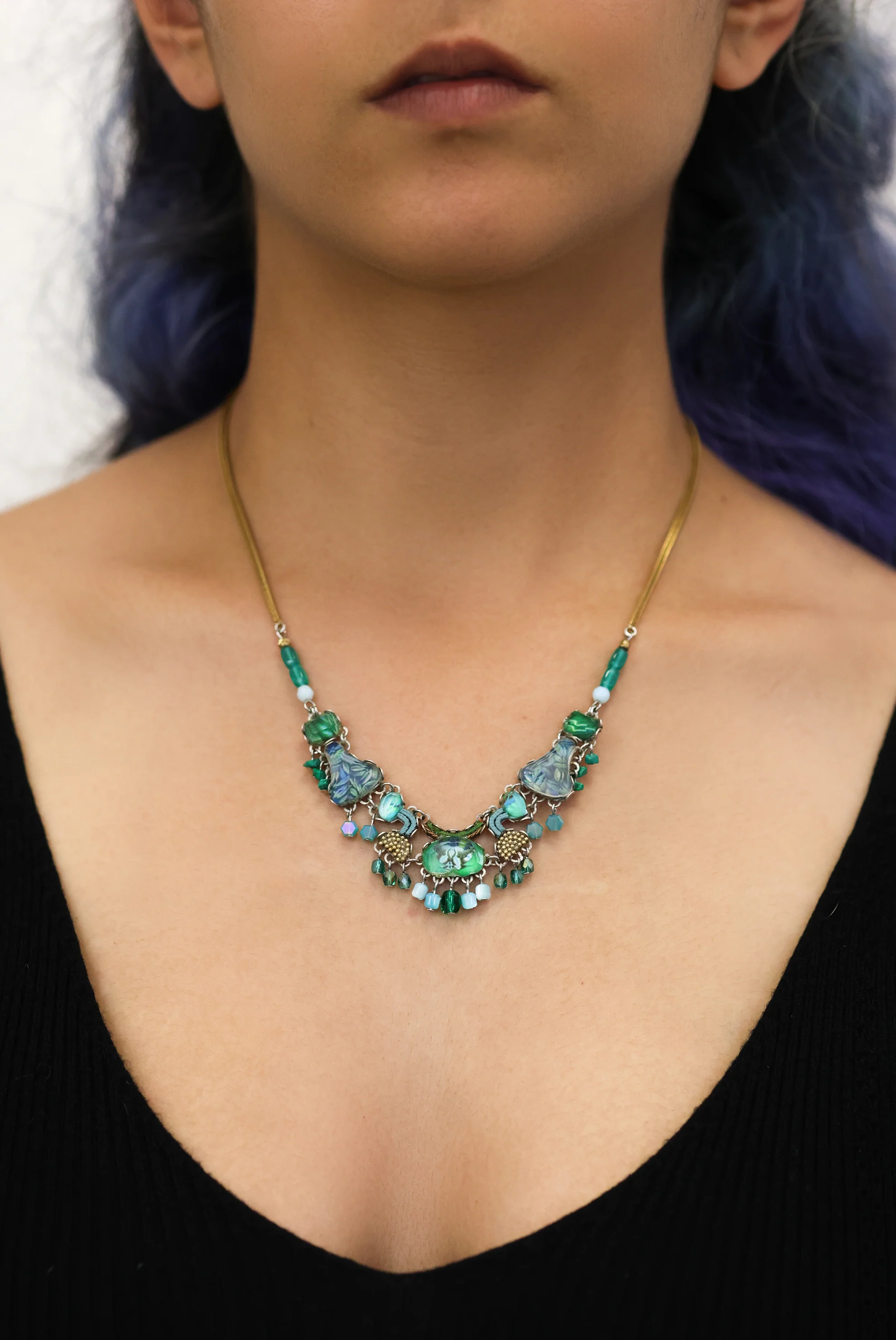 Plated Sterling Silver Necklace Featuring an Intricate Design with mixes of multicoloured Textile thread and multiple sizes of gemstones and beads. The main colours include tones of blue and green. | on model