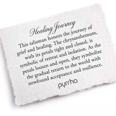 A Pyrrha note describing the Healing Journey talisman. It reads, "This talisman honors the journey of grief and healing. The chrysanthemum, with its petals tight and closed, is symbolic of retreat and isolation. As the petals loosen and open, they symbolize the gradual return to the world with newfound acceptance and resilience."