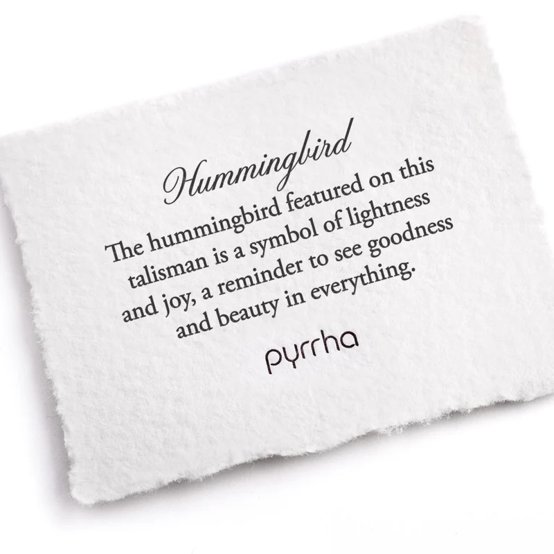 A Pyrrha Note describing the hummingbird talisman. It reads, "The hummingbird featured on this talisman is a symbol of lightness and joy, a reminder to see goodness and beauty in everything."