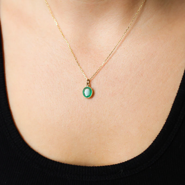 A colourful 14k Yellow Gold Emerald charm that can be worn as a standalone pendant or added to a layered stack. | on model