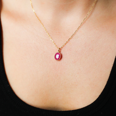 A colourful 14k Yellow Gold ruby charm that can be worn as a standalone pendant or added to a layered stack. | on model