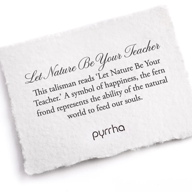 A Pyrrha note describing the Let nature Be Your Teacher talisman. It reads, This talisman reads 'Let Nature Be Your Teacher.' A symbol of happiness, the fern frond represents the ability of the natural world to feed our souls."