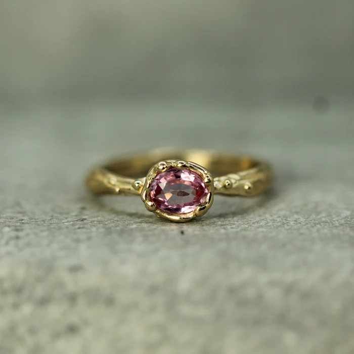 solid 14k yellow gold Ring featuring a .6ct oval pink sapphire