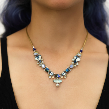 Plated Sterling Silver Necklace Featuring many variations of beads and gemstones. The predominant colours are blue white and gold, with interconnecting pendants all strung together with a large oval gemstone below the main body. | on model