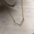 A mix of sterling silver and 14k yellow gold fill necklace splkit between a flat bar of gold, and beads of silver shaped to create a V