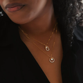 A mix of sterling silver and 14k yellow gold necklace shaped like a circle, half being  beads of silver, and the other half flat gold. in the centre of the ring is an opal gemstone, connected to the ring | on model