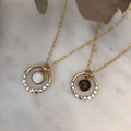 A mix of sterling silver and 14k yellow gold necklace shaped like a circle, half being  beads of silver, and the other half flat gold. in the centre of the ring is an opal gemstone, connected to the ring