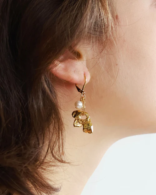 Short gold earrings adorned with a flower-shaped pewter pendant and a pearl | on model