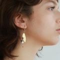 Short gold earrings with a winged pewter pendant and a cluster of colorful pearls | on model
