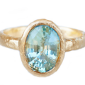 An oval blue-green sapphire, alive with the shifting colours of water, is cradled in hand-sculpted 14k yellow gold.