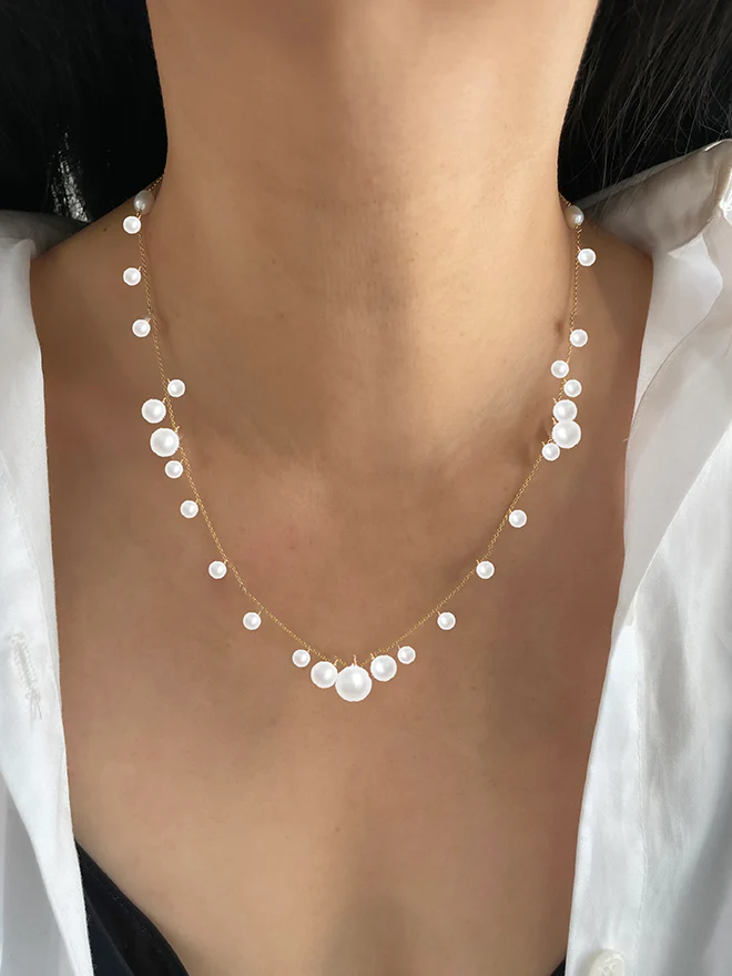 14k Yellow Gold Necklace featuring many varying sizes of pearls strung about a thin gold chain, creating a "bubbly" appearance | on model