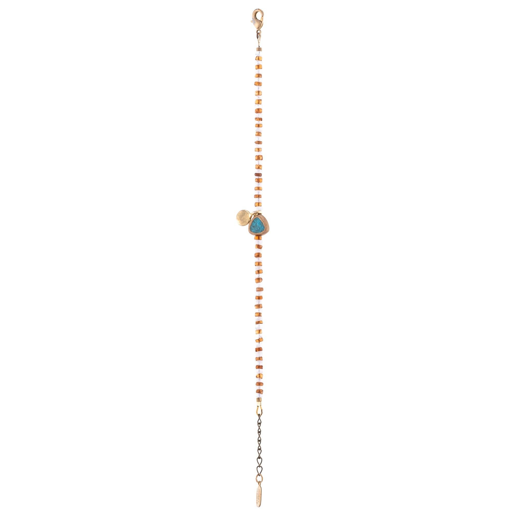This unique bracelet features a combination of Hessonite, Moonstone, brass-edged Turquoise, and a 14K gold-plated brass coin pendant, all showcased in a striped pattern. 