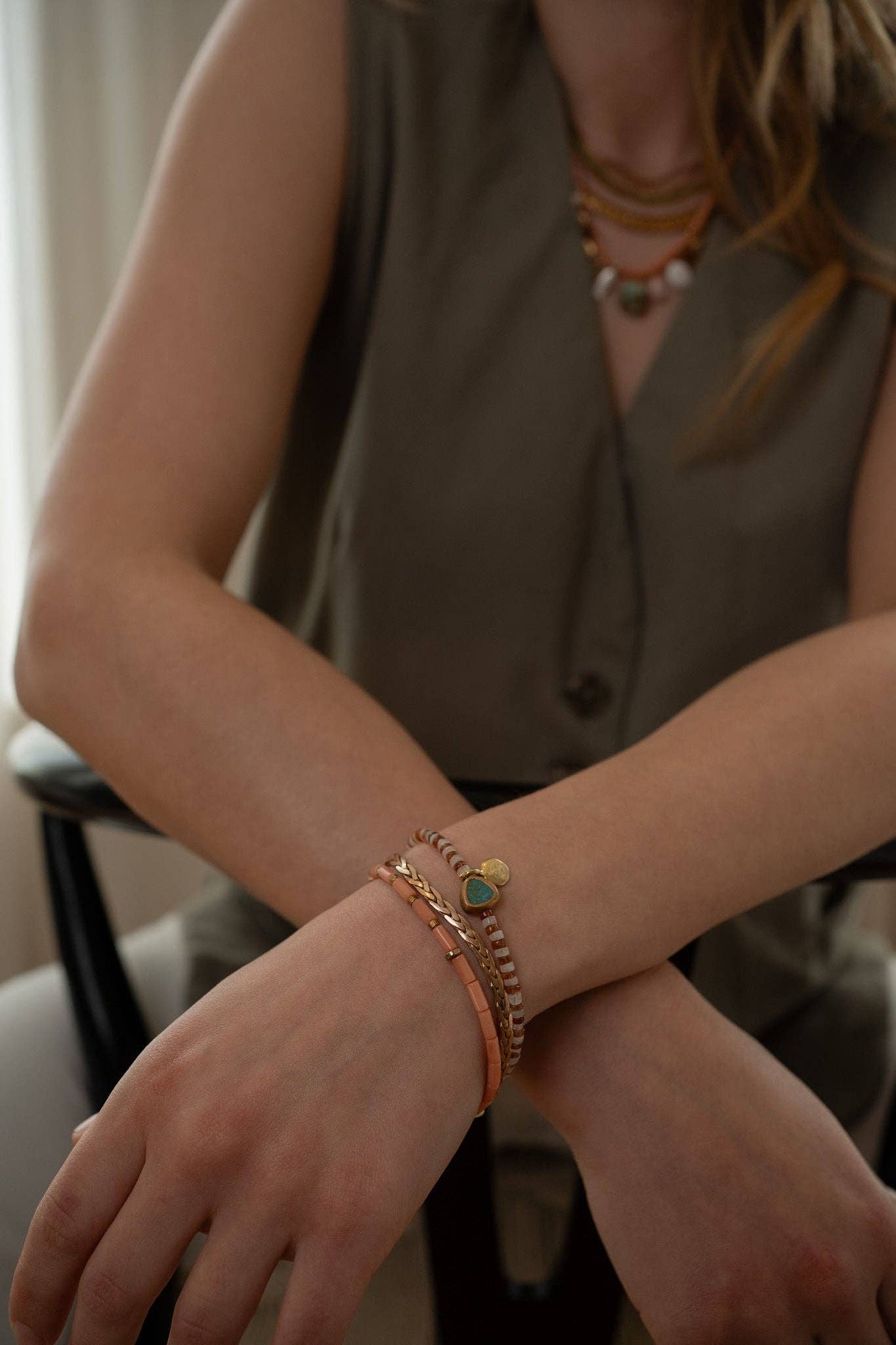 This unique bracelet features a combination of Hessonite, Moonstone, brass-edged Turquoise, and a 14K gold-plated brass coin pendant, all showcased in a striped pattern. | on model