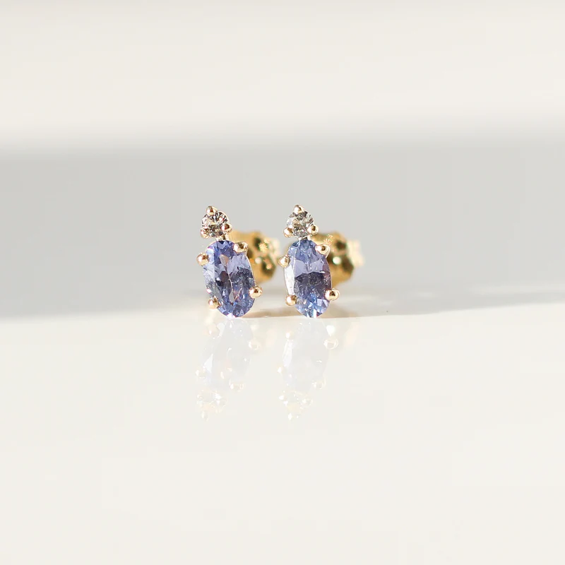 Lilac purple oval cut sapphire earrings accented by a tiny colourless round cut sapphire in solid 14k Yellow Gold. 