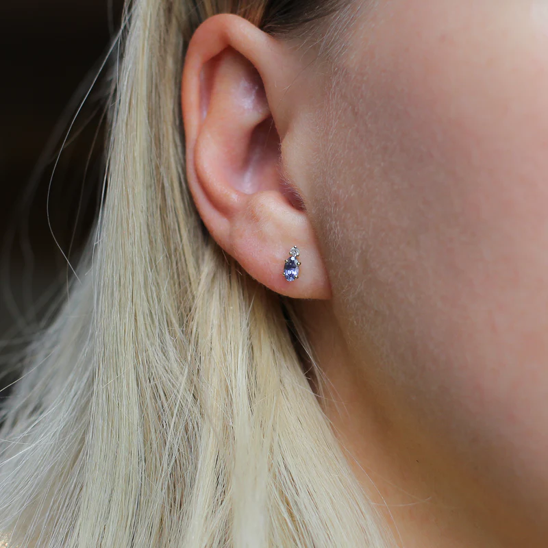 Lilac purple oval cut sapphire earrings accented by a tiny colourless round cut sapphire in solid 14k Yellow Gold.  | on model