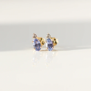 Lilac purple oval cut sapphire earrings accented by a tiny colourless round cut sapphire in solid 14k Yellow Gold. 