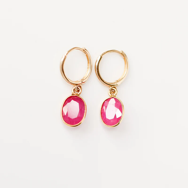 These 14k Yellow Gold hoops feature a delicate oval ruby charm