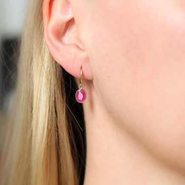 These 14k Yellow Gold hoops feature a delicate oval ruby charm | on model