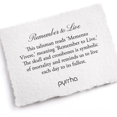 A Pyrrha note describing the Remember to Live talisman. It reads, "This talisman reads 'Memento Vivere' meaning 'Remember to Live.' The skull and crossbones is symbolic of mortality and reminds us to live each day to its fullest."