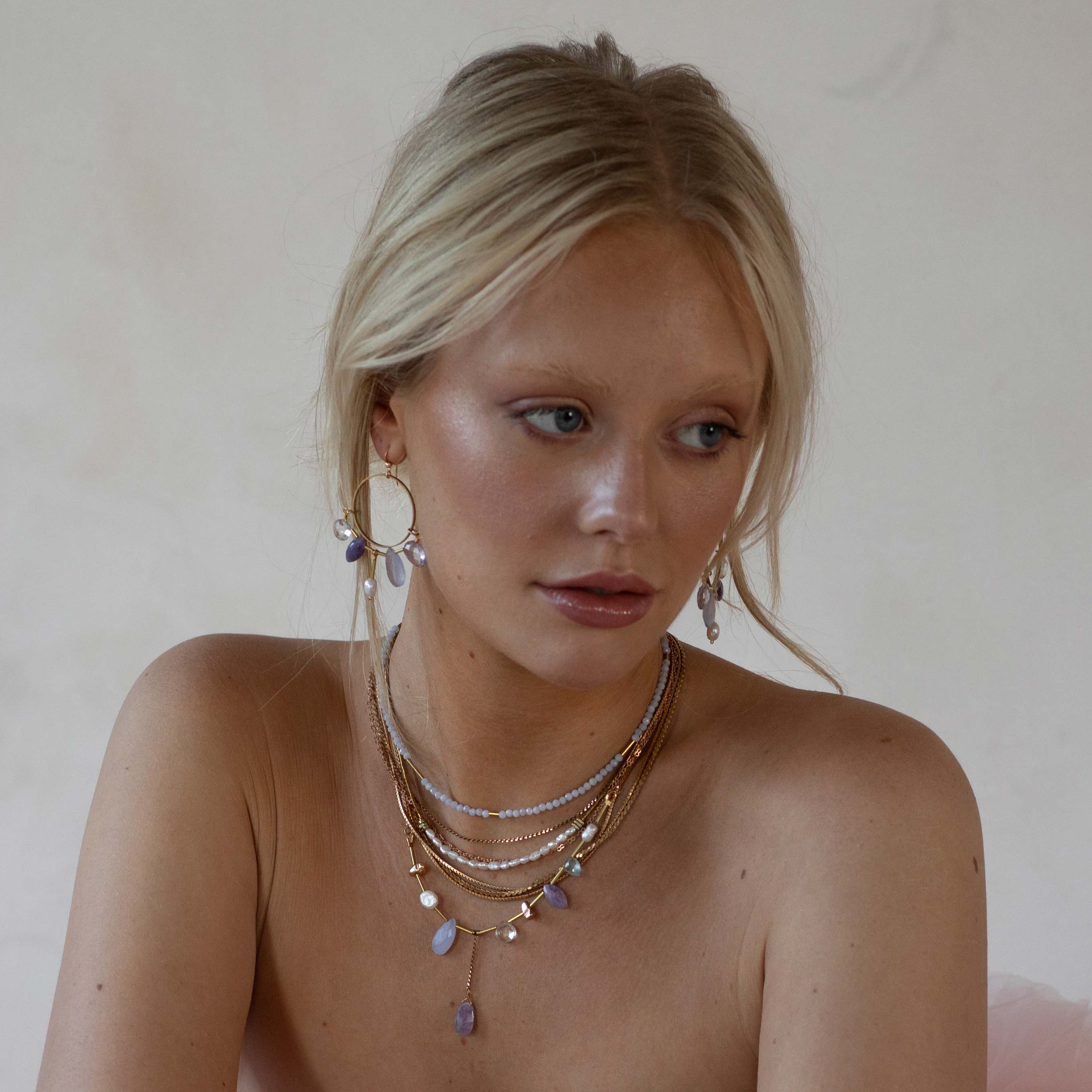 Austra Earrings ,Created with lightweight materials,  featuring an array of serene gemstones with facets that reflect light for a subtle yet stunning effect.  | on model