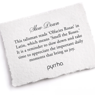 A Pyrrha note describing the Slow Down talisman. It reads, "This talisman reads 'Olfacies Rosas' in Latin, which means 'Smell the Roses.' It is a reminder to slow down and take time to appreciate the important daily moments that bring us joy."