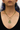 Plated Sterling Silver Necklace predominantly featuring a texttile design primarily black and yellow, with a tiger above it. Connected to it is  2  thin chains with small white gems hanging and a small green gemstone in the middle of the chains  | on model