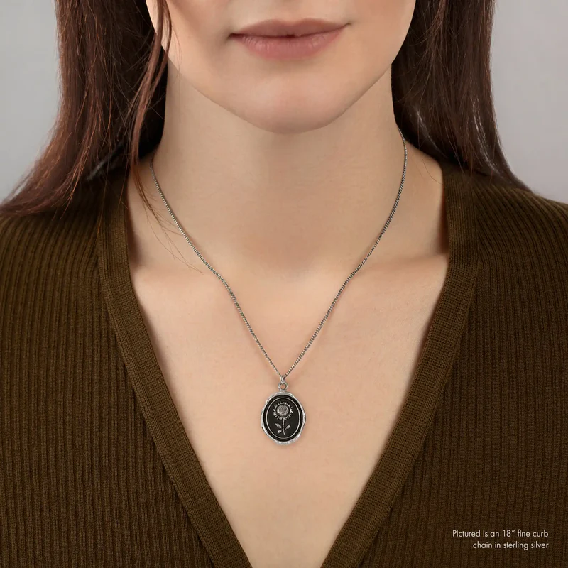 A Sterling SilverPyrrha Talisman With a black background depicting a Large Upright Sunflower | on model