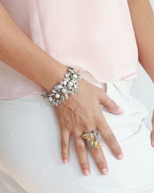 Chunky silver bracelet featuring threaded pearls and pewter pendants | on model