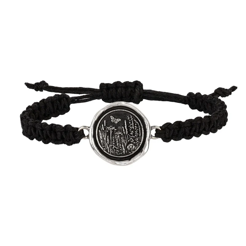 Black Braided Bracelet with a Sterling Silver talisman depicting a butterfly flying above a field of various flora and grass