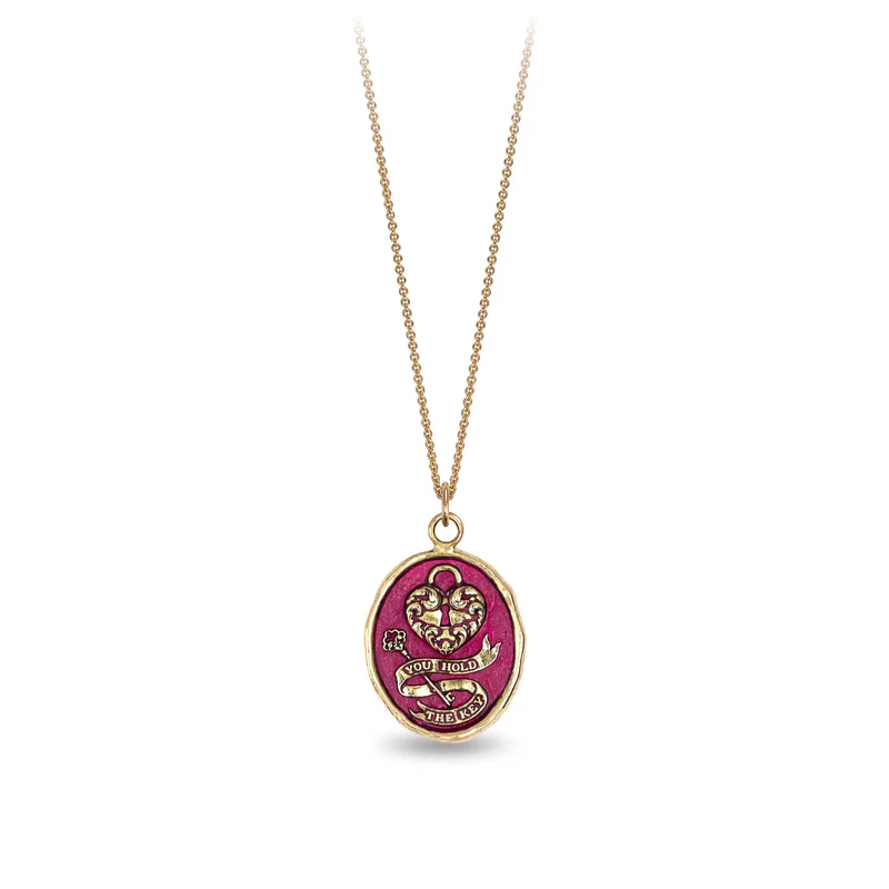 14k Yellow gold talisman necklace with a bright red background depicting a Large lock in the shape on a heart above a key with a ribbon that says "You Hold The key"