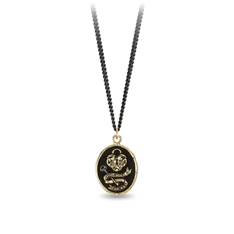 Black Sterling SIlver necklace with a 14k yellow gold talisman depicting a Large lock in the shape on a heart above a key with a ribbon that says "You Hold The key"