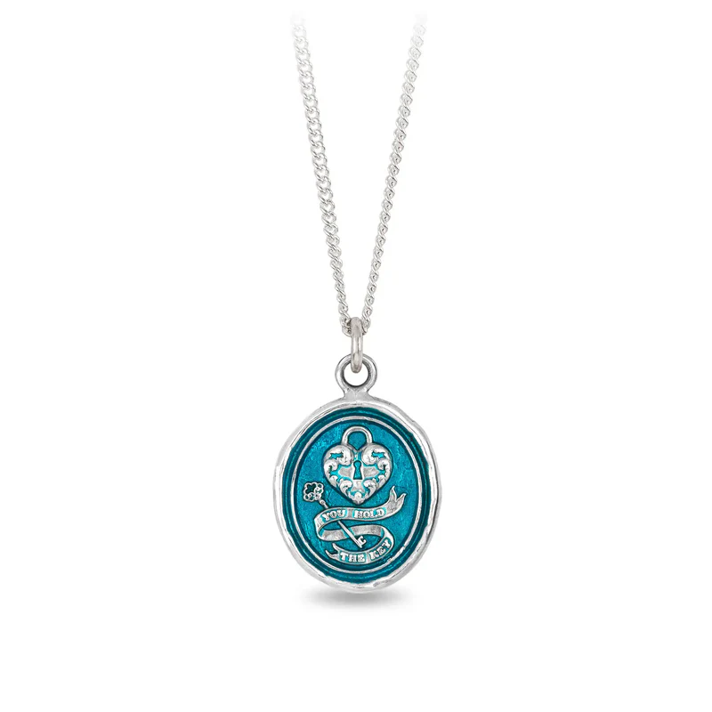 Sterling Silver talisman with a light blue background depicting a heart with a lock on it, above a key surrounded by a ribbon with the words, "you hold the key" written on it
